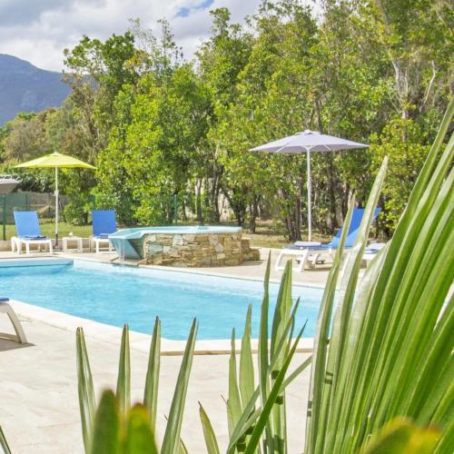 une piscine avec parasols et chaises et une table de billard dans l'établissement Maison familiale avec piscine à Pietracorbara, à Pietracorbara