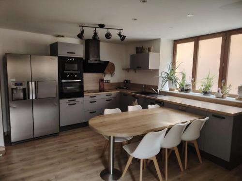 - une cuisine avec une table en bois et des chaises blanches dans l'établissement La Casa Beaujolaise, à Charnay