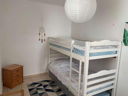 Ce lit superposé blanc se trouve dans un dortoir doté d'une lampe. dans l'établissement La corvette des mers Saint Hilaire de Riez, à Saint-Hilaire-de-Riez