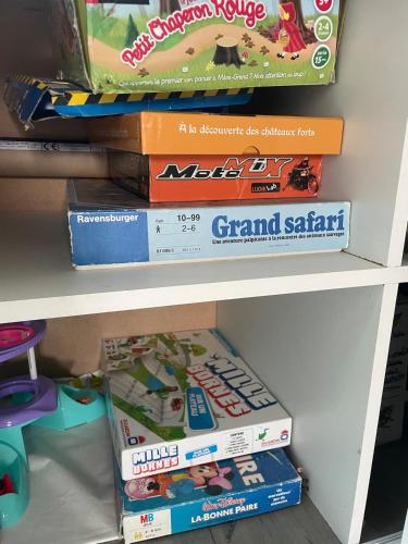 a shelf with a stack of board games at Maison à louer in Yèvres