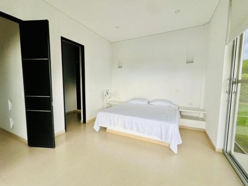 a white bedroom with a bed and a window at La finca in La Mesa