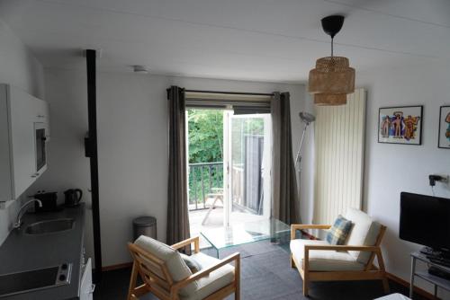 un soggiorno con divano, sedie e finestra di villa Flore, studio's a Bergen aan Zee