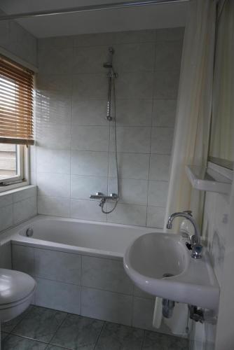un bagno con vasca, lavandino e WC di villa Flore, studio's a Bergen aan Zee