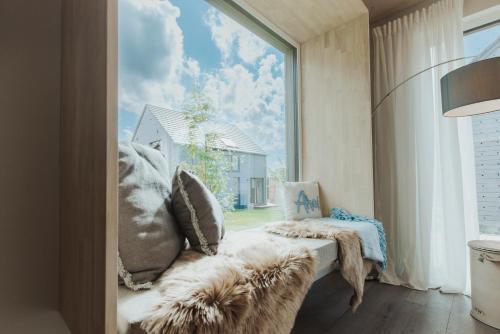 a room with a large window and a couch with pillows at NEU "Rügen Resørt Sagard" großzügiges, gemütliches Familienhaus "Alva" mit Terrasse in Sagard