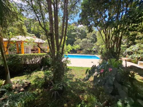 a yard with a swimming pool and trees at Chácara com 05 dormitórios, piscina e Lazer LT0040 in Juquitiba