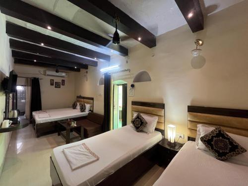 a hotel room with two beds and a desk and a table at Foreigners Inn in Varanasi