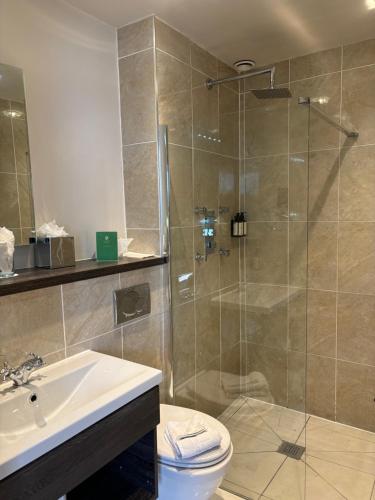 a bathroom with a shower and a toilet and a sink at Hatherley Manor Hotel & Spa in Gloucester