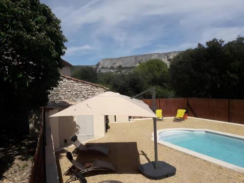 un parasol et une chaise à côté de la piscine dans l'établissement Au pied de la montagne, à Lioux