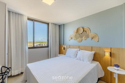 a bedroom with a white bed and a window at Modern and sophisticated apartments near the beach in Maraú – VLL in Marau