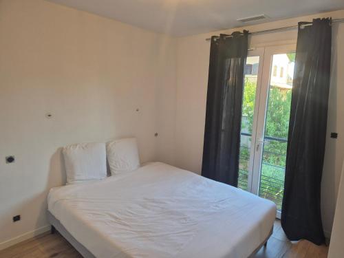 a bed in a room with a large window at T3 rdc mimosas in Juvignac