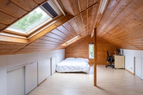 une chambre mansardée avec un lit et une fenêtre dans l'établissement Grande maison entière RER B direct Paris & Orly, à Antony