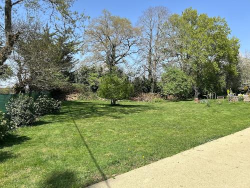 a yard with green grass and trees and a sidewalk at Maison de charme in Pluneret