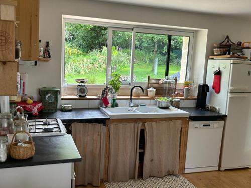 a kitchen with a sink and a large window at Maison de charme in Pluneret