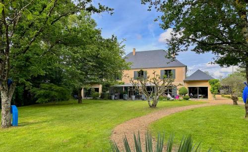 une maison avec une cour avec de l'herbe et des arbres dans l'établissement Gîte du Soleil dans la Ruelle - La Grouas, à Étival-lès-Le Mans