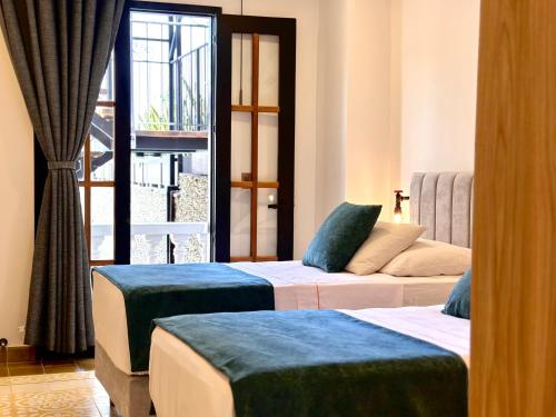a hotel room with two beds and a window at La Brisa Loca Hostel in Santa Marta