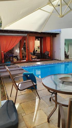 a pool with a table and chairs and a table and a swimming pool at Pousada Pé na Areia Guarujá in Guarujá