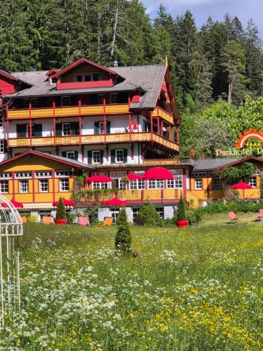 a large building with red umbrellas in a field of flowers at Parkhotel Sole Paradiso in San Candido