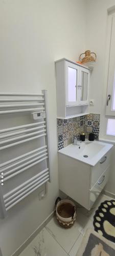 une salle de bain blanche avec un lavabo et un miroir dans l'établissement Cosy Home CDG PARIS ASTÉRIX DISNEY, à Goussainville
