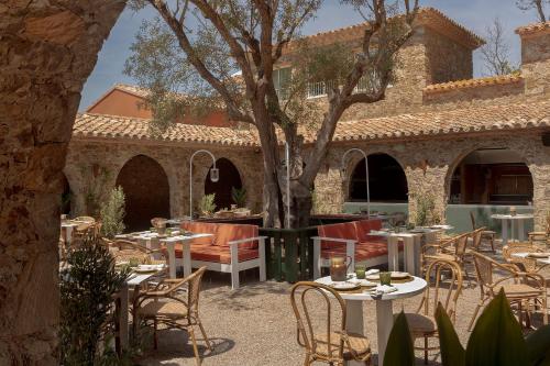 an outdoor patio with tables and chairs and a tree at Finca Victoria, a Member of Design Hotels in Begur