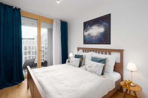een slaapkamer met een groot bed met blauwe gordijnen bij Stylish Flat by the Metro in Praag