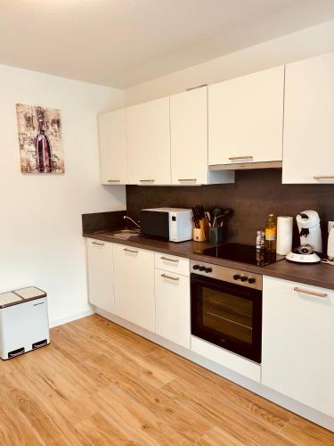 a kitchen with white cabinets and a stove top oven at Swiss City Apartments Rust in Rust