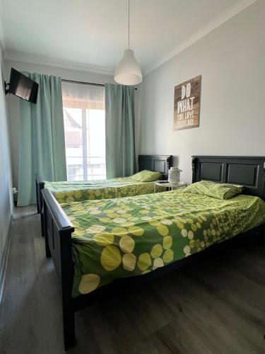 a bedroom with two beds with green comforter at Bibel Ocean Home Sunset by the sea in Vila Praia de Âncora