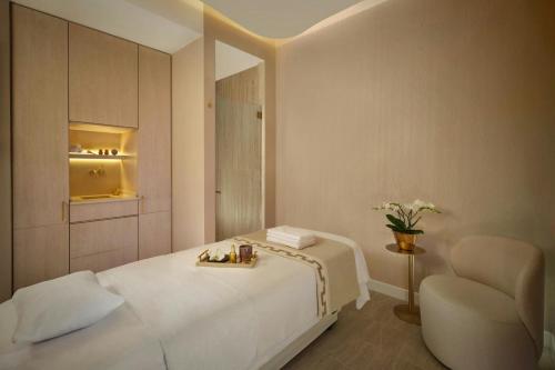 a bedroom with a white bed and a chair at The Ritz-Carlton Hotel de la Paix, Geneva in Geneva