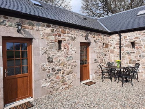 a stone building with a patio with a table and chairs at A Stylish Country Retreat! in Keilour