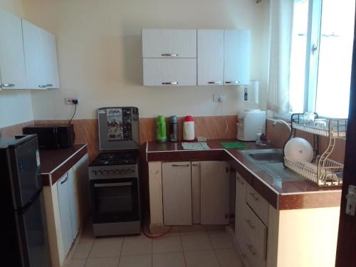 モンバサにあるMtwapa Homes M Luxury Apartmentsの白いキャビネットとコンロ付きオーブンを備えたキッチン