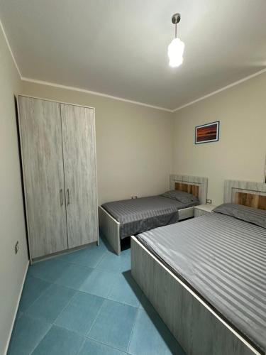 a bedroom with two beds and a cabinet at Eri Apartments 4 in Shëngjin