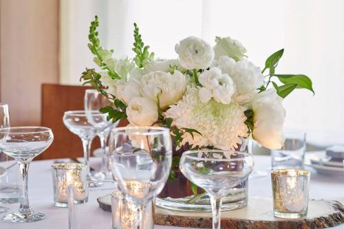 a vase filled with white flowers on a table with glasses at Courtyard Portland Downtown / Convention Center in Portland