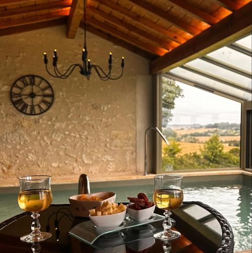 - une table avec de la nourriture et des verres à vin ainsi qu'une fenêtre dans l'établissement Domaine Léa Chanflaur - Spa - La maison du bonheur, à Terraube