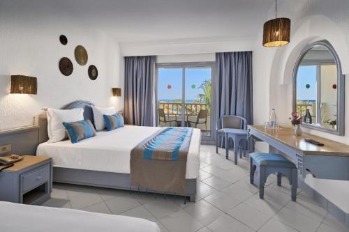 a hotel room with a bed and a desk and chairs at Les Quatre Saisons Ex Baya Beach in Djerba