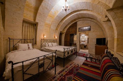a bedroom with two beds in a room with an arch at Konak Bezirhane Cave Otel in Urgup