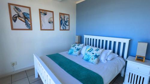 a bedroom with a white bed with blue walls at Santos View 40 in Mossel Bay