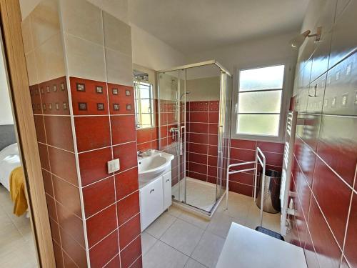 a bathroom with red tiles and a shower and a sink at Bel appartement Erbalunga- A deux pas de la plage in Brando