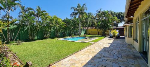 a backyard with a swimming pool and a lawn at Encantadora Chácara com Piscina em Itanhaém in Itanhaém