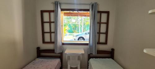 a small room with two beds and a window at Encantadora Chácara com Piscina em Itanhaém in Itanhaém