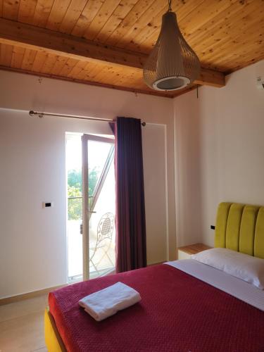 a bedroom with a bed and a large window at Lahuta e Vjeter Agroturizem in Laç