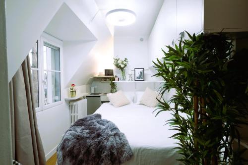 une chambre avec un lit blanc et une plante dans l'établissement Tour Eiffel - Invalides - Studio, à Paris