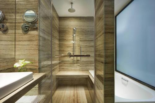 a bathroom with a shower and a bathtub at Courtyard by Marriott Bandung Dago in Bandung