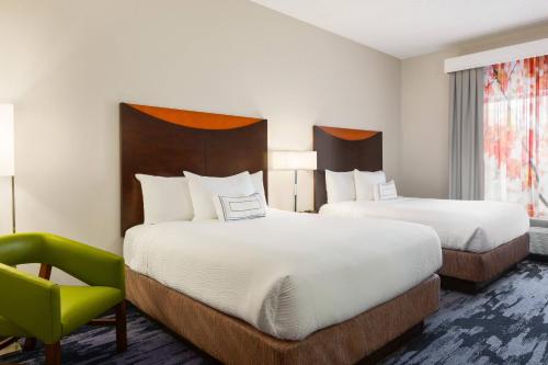 a hotel room with two beds and a green chair at Fairfield Inn & Suites Jacksonville West/Chaffee Point in Jacksonville