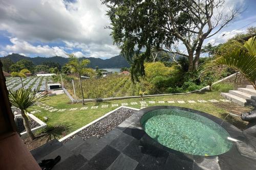 a small swimming pool in a garden with a view of the water at Nirwana Kintamani in Kubupenlokan