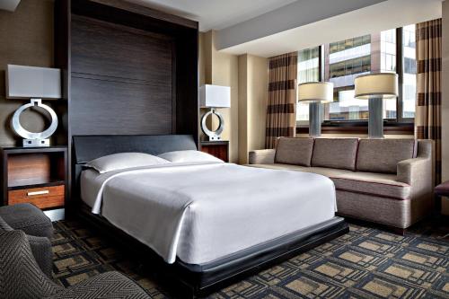 a bedroom with a large white bed and a couch at Sheraton New York Times Square Hotel in New York