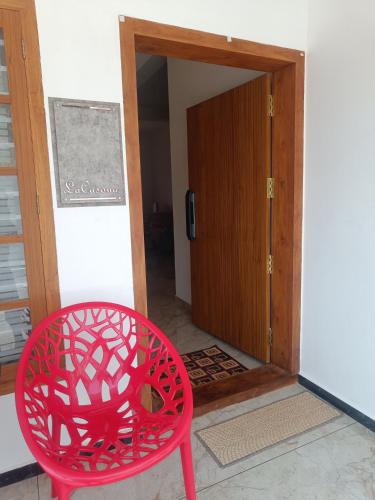 a red chair sitting in front of a door at La-Casona in Kottayam