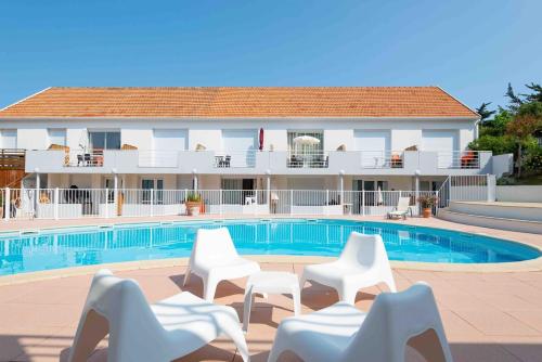 une piscine avec des chaises blanches et un bâtiment dans l'établissement Appartement 350 m de la plage avec terrasse bois, à Saint-Jean-de-Monts
