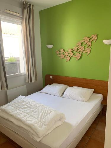 Ce lit se trouve dans une chambre dotée d'un mur vert. dans l'établissement Appartement 350 m de la plage avec terrasse bois, à Saint-Jean-de-Monts