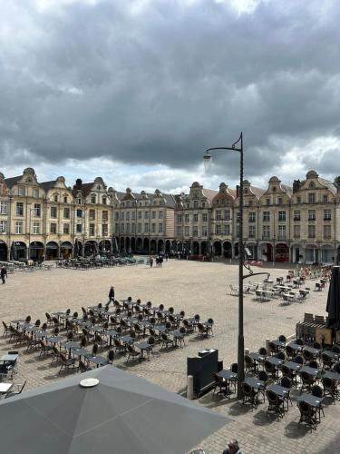 un grand bâtiment avec des tables et des chaises dans une cour dans l'établissement Beffroi's Cosiest Place, à Arras