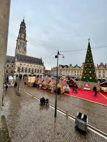 un arbre de Noël devant un grand bâtiment dans l'établissement Beffroi's Cosiest Place, à Arras