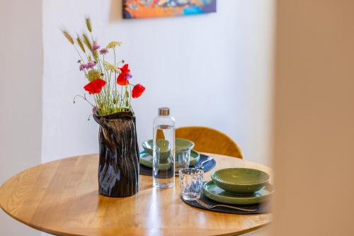 a table with a vase of flowers and plates on it at Casa Annunziata Guest House in Ruffano
